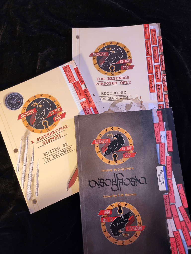 A stack of the three released issues of Archive of the Odd against a black backdrop.